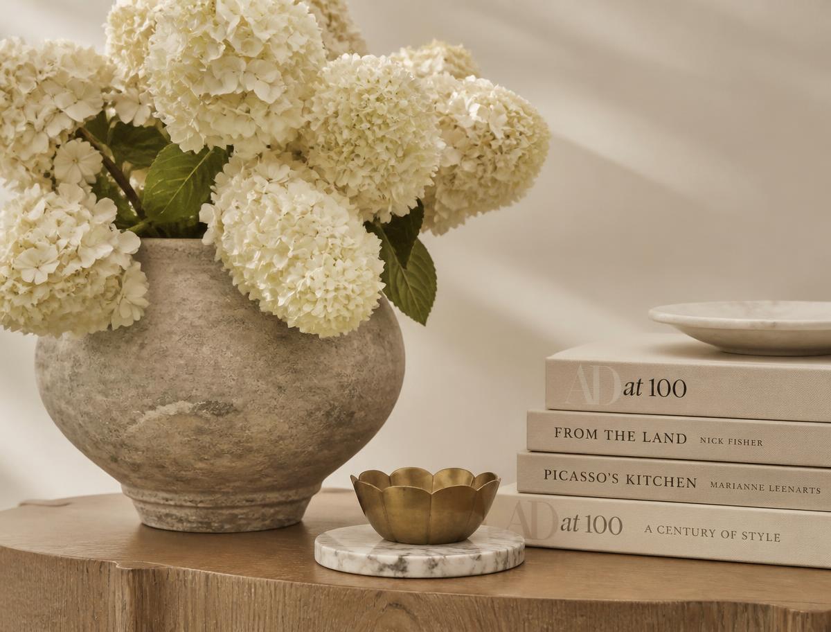 Hydrangeas in a stone vase beside a stack of books